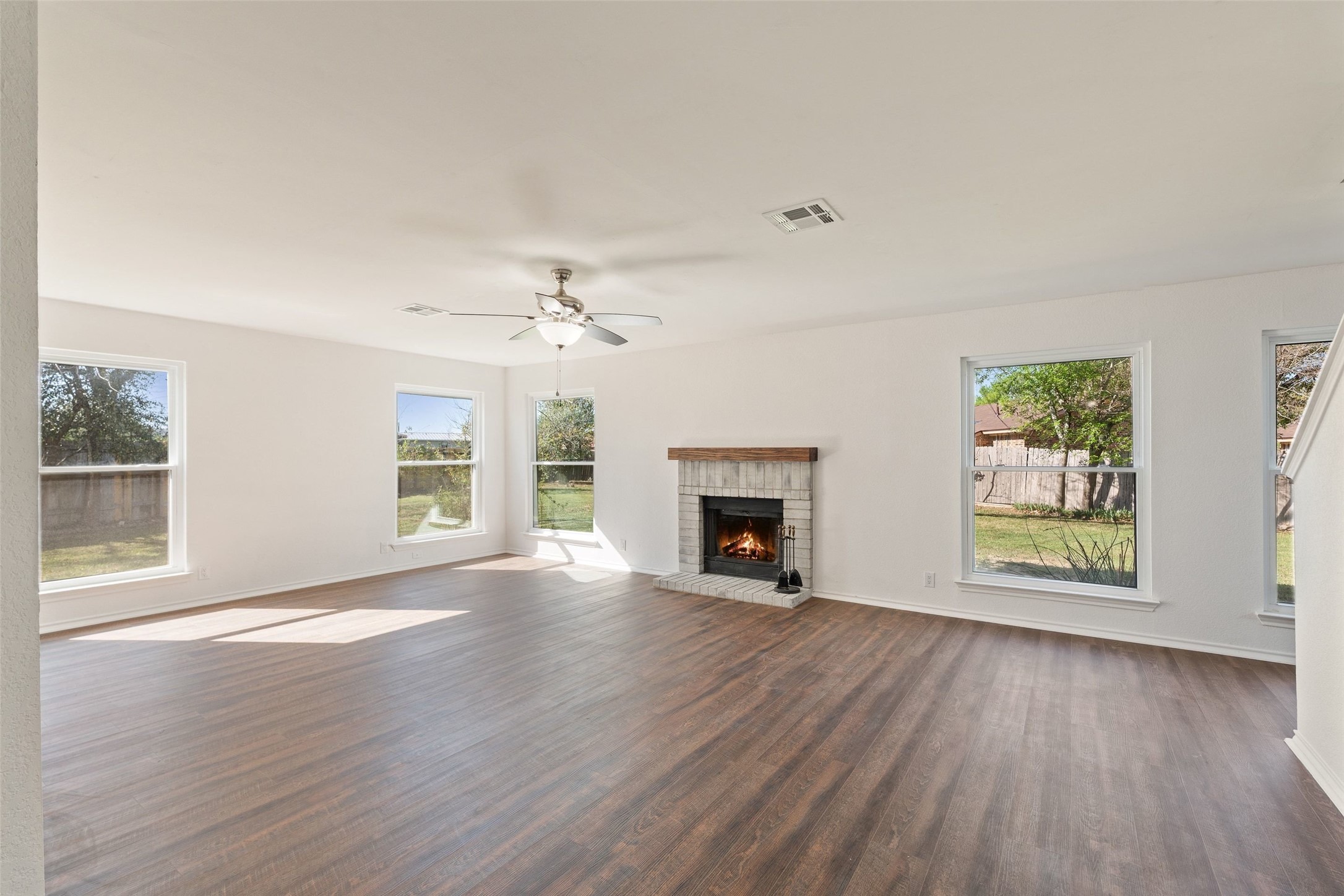 1011 Hayden Way Round Rock, TX 78664 - Photo 3 of 23 an empty room with windows fireplace and wooden floor