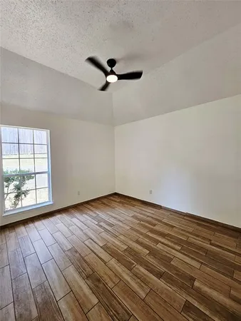 a view of empty room with wooden floor and fan