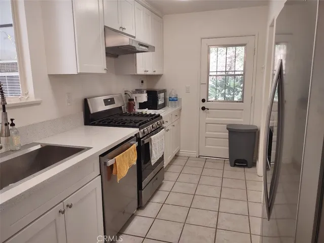 a kitchen with a sink a stove cabinets and a window