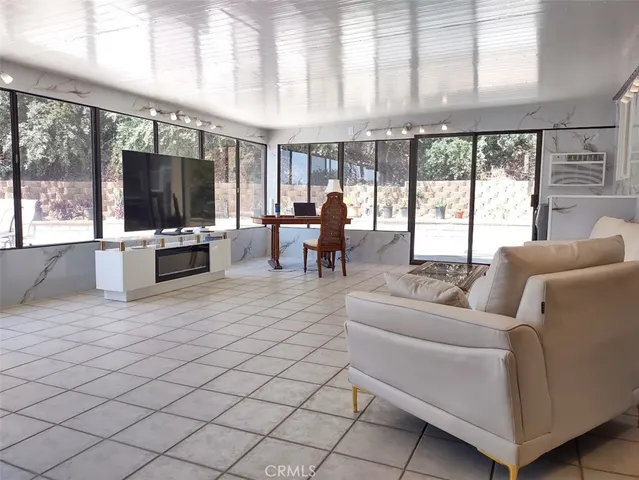 a living room with furniture a flat screen tv and floor to ceiling window