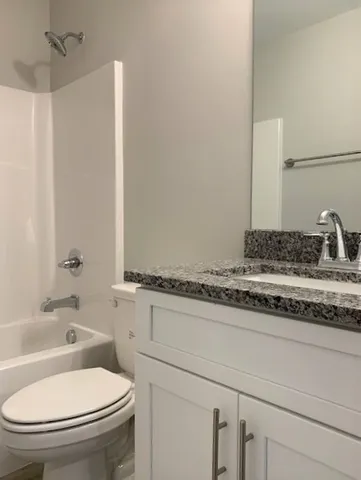 a bathroom with a granite countertop toilet sink and mirror