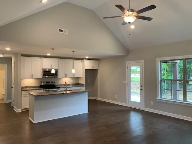 a kitchen with stainless steel appliances kitchen island granite countertop a stove a sink and a refrigerator