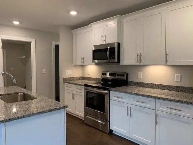 a kitchen with granite countertop white cabinets and stainless steel appliances