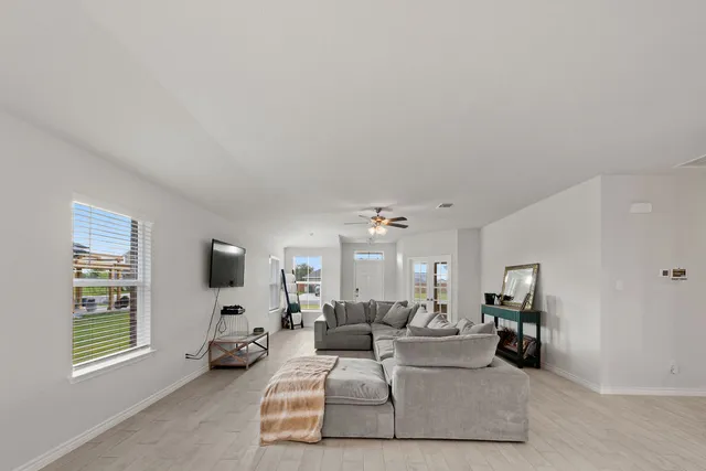 an empty room with windows and ceiling fan