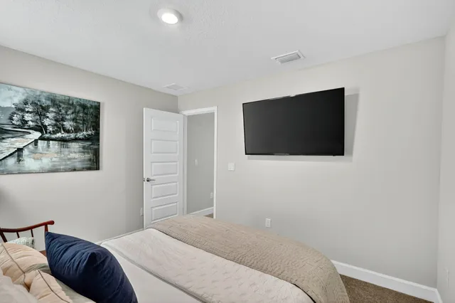 a bedroom with a bed a dresser and painting on the wall