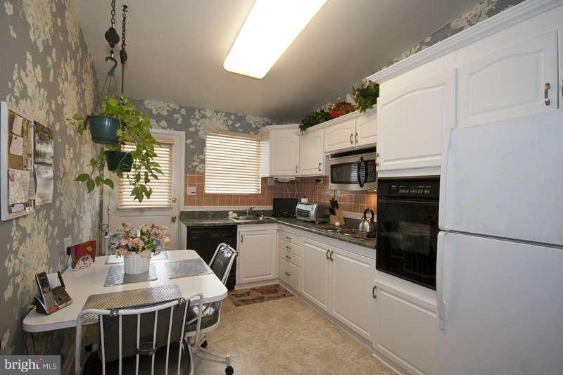 8119 Scotts Level Road Baltimore, MD 21208 - Photo 7 of 24 a kitchen with stainless steel appliances granite countertop a refrigerator a stove a sink dishwasher and white cabinets with wooden floor