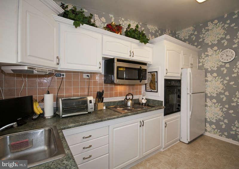 8119 Scotts Level Road Baltimore, MD 21208 - Photo 9 of 24 a kitchen with stainless steel appliances granite countertop a stove microwave and refrigerator