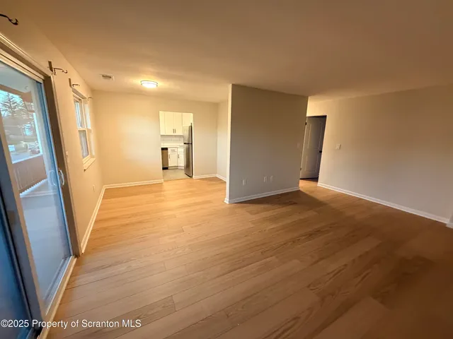 a view of a big room with wooden floor and windows