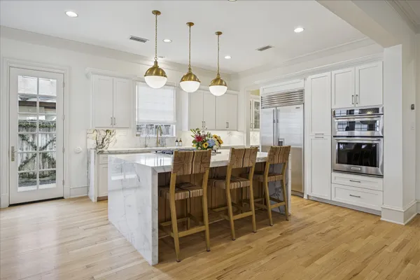 a dining room filled with furniture a chandelier a kitchen view and a fireplace