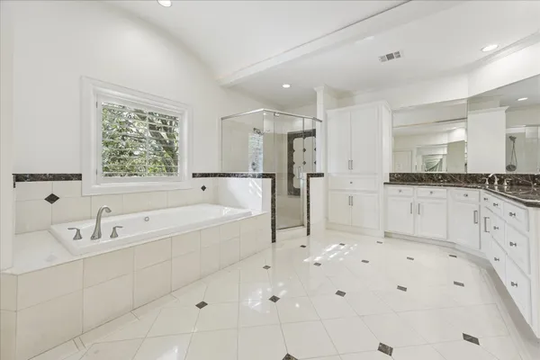 a spacious bathroom with a bathtub shower sink and mirror