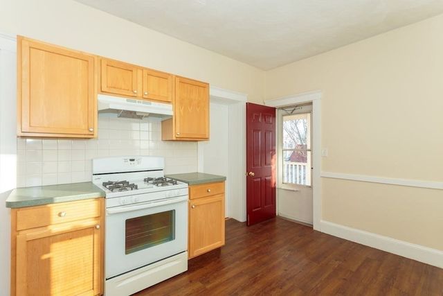 a kitchen with a stove top oven cabinets and a wooden floor