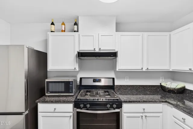 a kitchen with granite countertop stainless steel appliances a stove a sink and cabinets