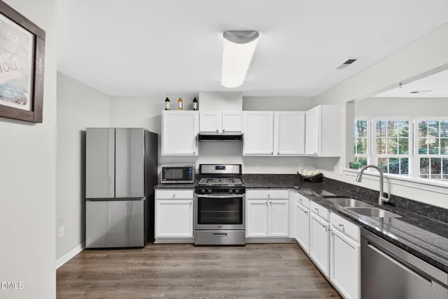 a kitchen with granite countertop a refrigerator stove a sink and dishwasher with wooden floor