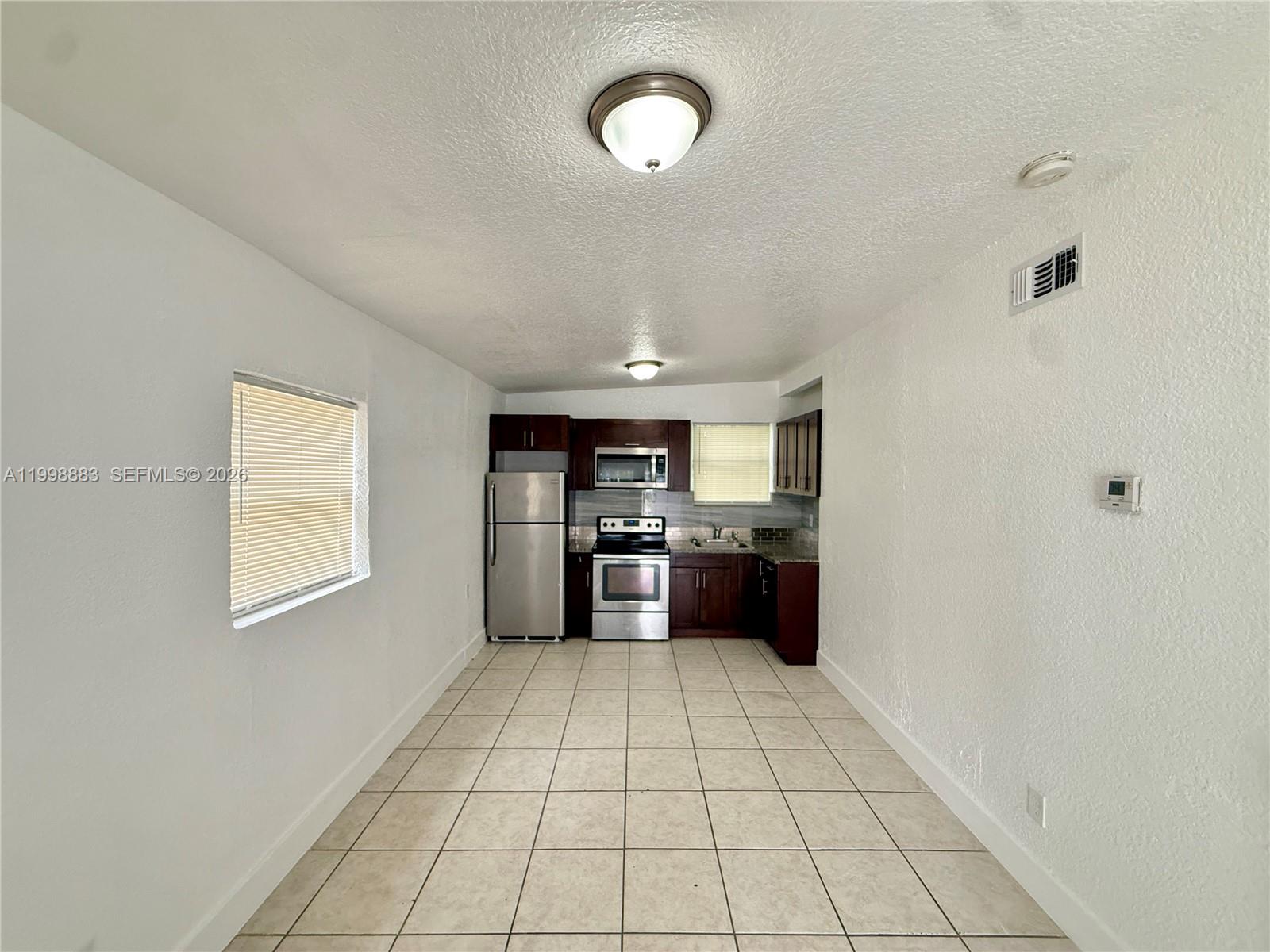 1345 Northwest 55th Street, Unit 2 Miami, FL 33142 - Photo 2 of 9 a kitchen with granite countertop a refrigerator and a stove top oven