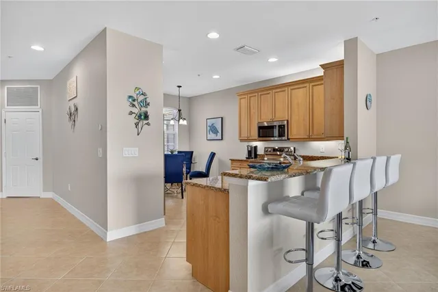 a view of kitchen with kitchen island stainless steel appliances refrigerator stove dining table and chairs