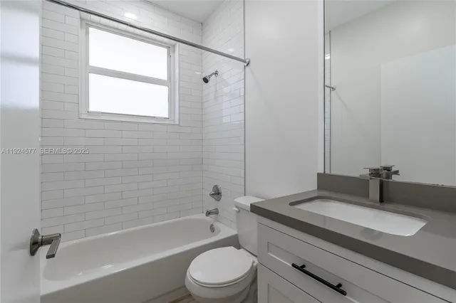 a bathroom with a granite countertop sink toilet a mirror and a bathtub