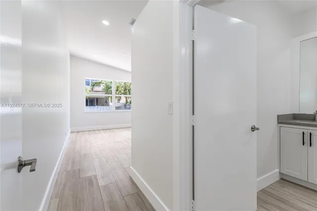 a view of a hallway with wooden floor and a bathroom