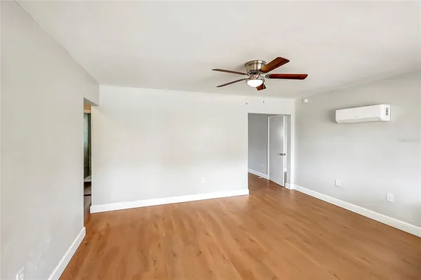 an empty room with wooden floor and a ceiling fan