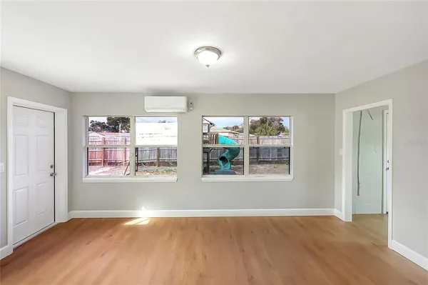 a view of an empty room with wooden floor and a window