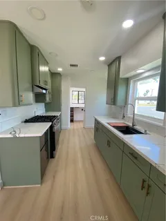 a large kitchen with a large counter top a sink stainless steel appliances and cabinets