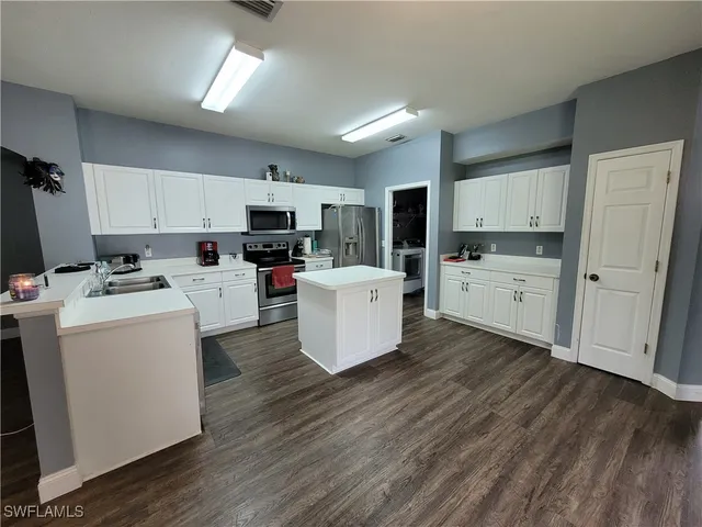 a kitchen with a sink wooden floor and black appliances