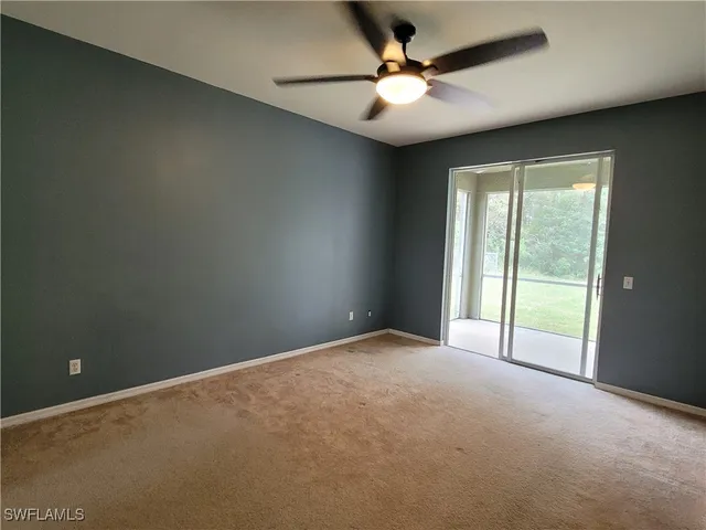 an empty room with chandelier fan and windows