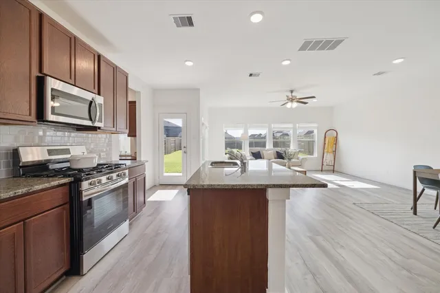 a kitchen with stainless steel appliances granite countertop a sink stove and refrigerator