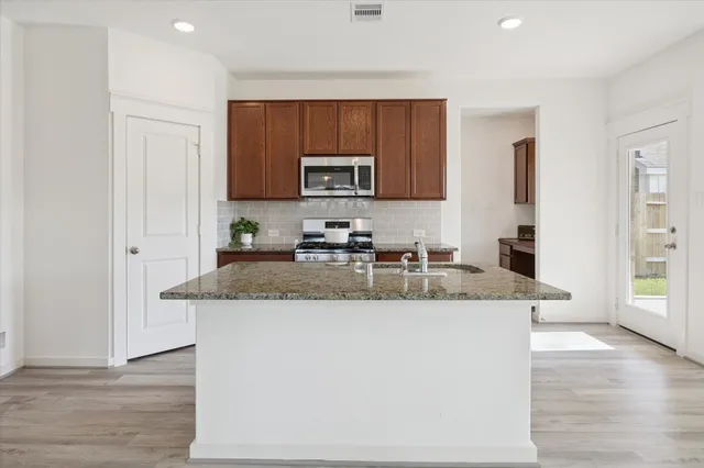 a kitchen with stainless steel appliances granite countertop a sink stove and cabinets