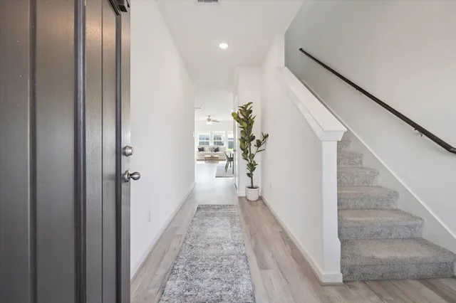 a view of a hallway with wooden floor and staircase