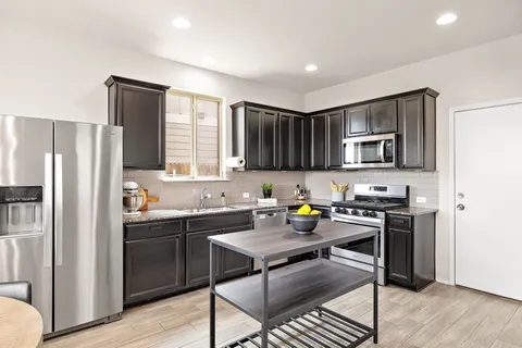 a kitchen with a sink a stove a refrigerator cabinets and wooden floor