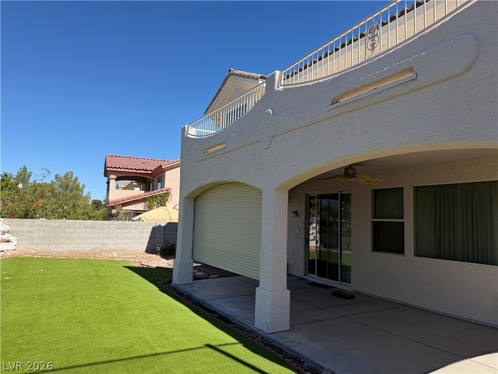 141 Rancho Maria Street Las Vegas, NV 89148 - Photo 27 of 30 An arched covered patio overlooks a grassy backyard with stucco-clad exterior architecture.