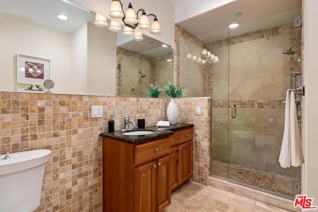 a bathroom with a sink a toilet a mirror and shower