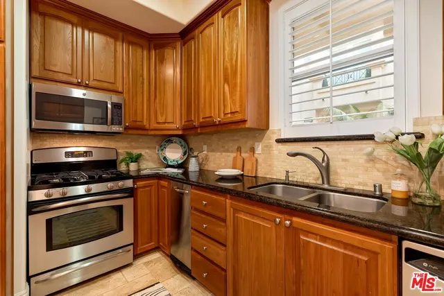 a kitchen with granite countertop wooden cabinets and a stove top oven