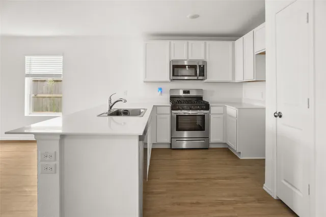 a kitchen with stainless steel appliances a stove microwave and sink