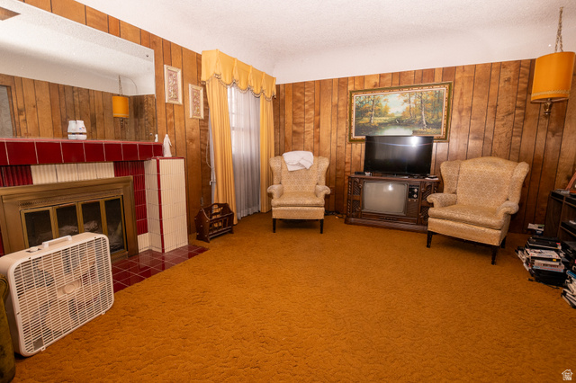 160 North 100 W Street Beaver, UT 84713 - Photo 12 of 36 Living area featuring a tile fireplace, wooden walls, heating unit, a textured ceiling, and carpet