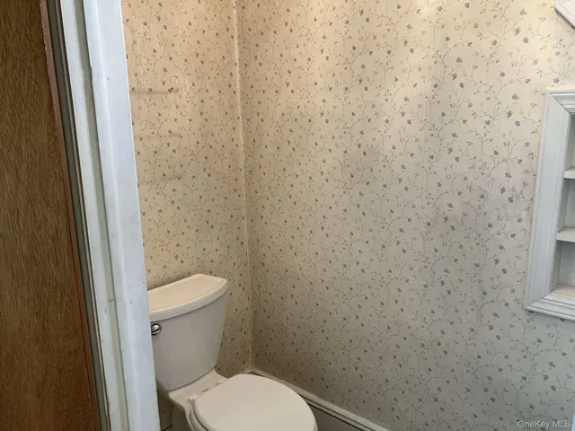 a white toilet sitting next to a white wall