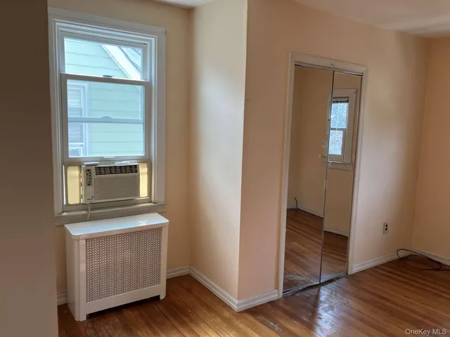 an empty room with wooden floor cabinet and windows