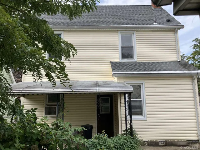a front view of a house with a tree