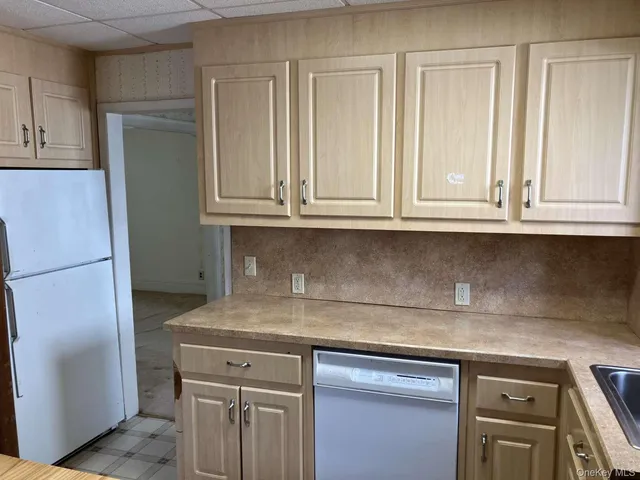 a kitchen with granite countertop white cabinets and refrigerator