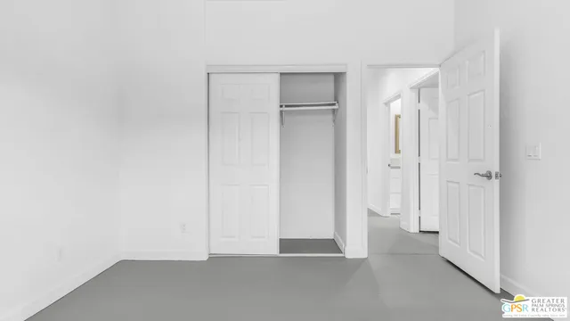 a view of an empty room with closet and a window