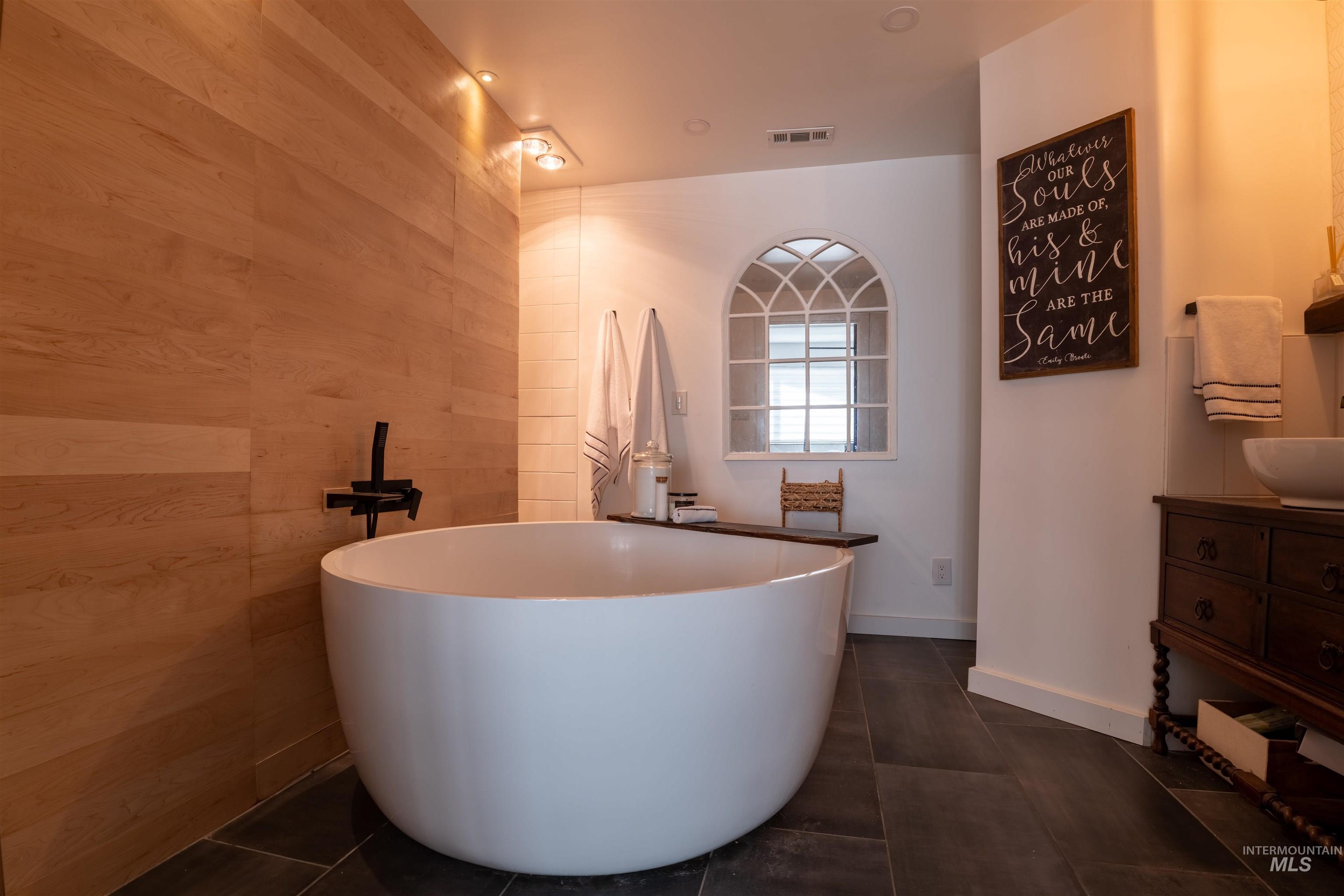 14526 Perfection Lane Caldwell, ID 83607 - Photo 14 of 24 Freestanding soaking tub with a wall-mounted matte black faucet, set against wood-finish paneling