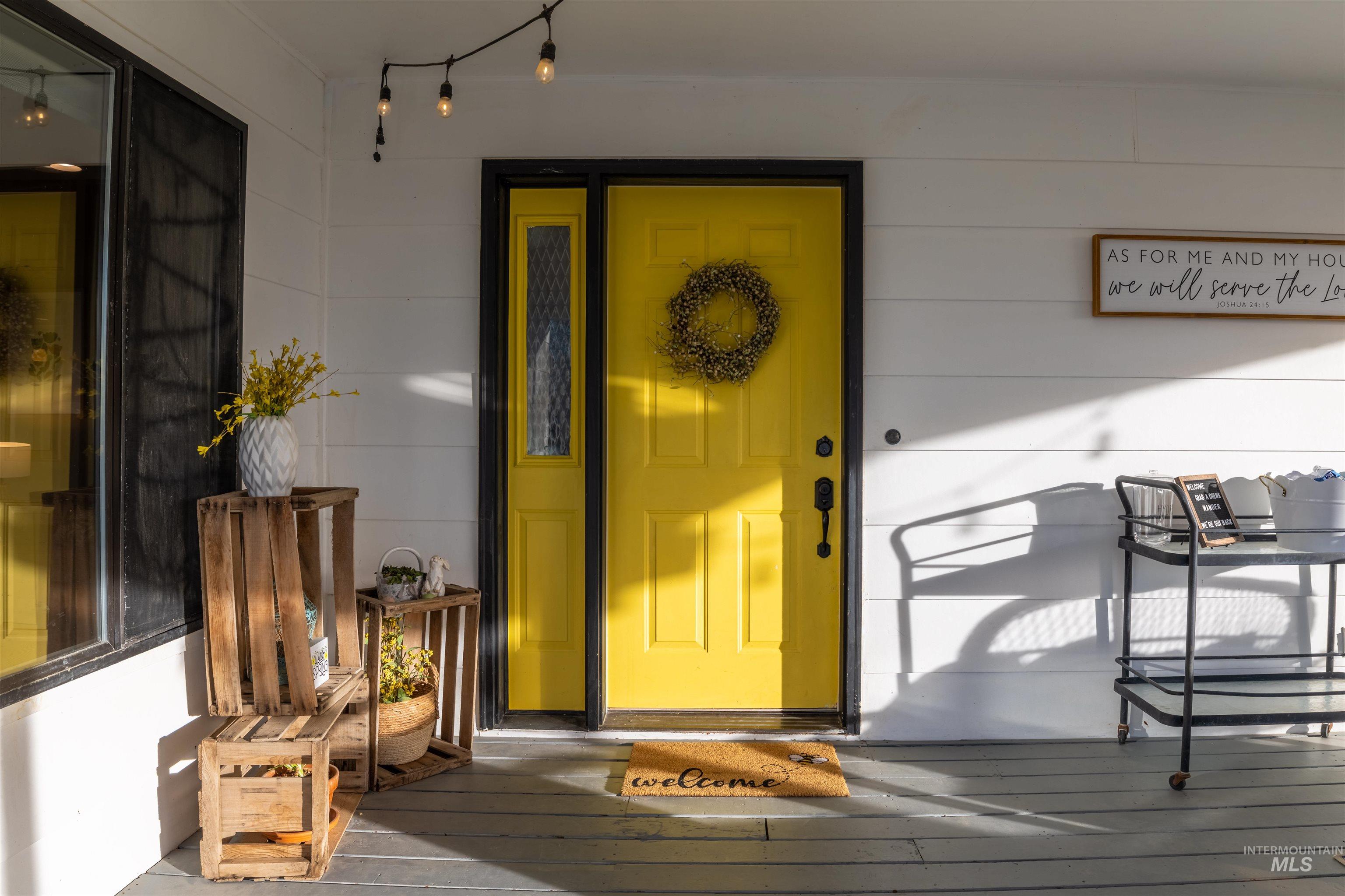 14526 Perfection Lane Caldwell, ID 83607 - Photo 2 of 24 Inviting front entry featuring a vibrant yellow door with black trim, a coordinating sidelight, and a decorative wreath