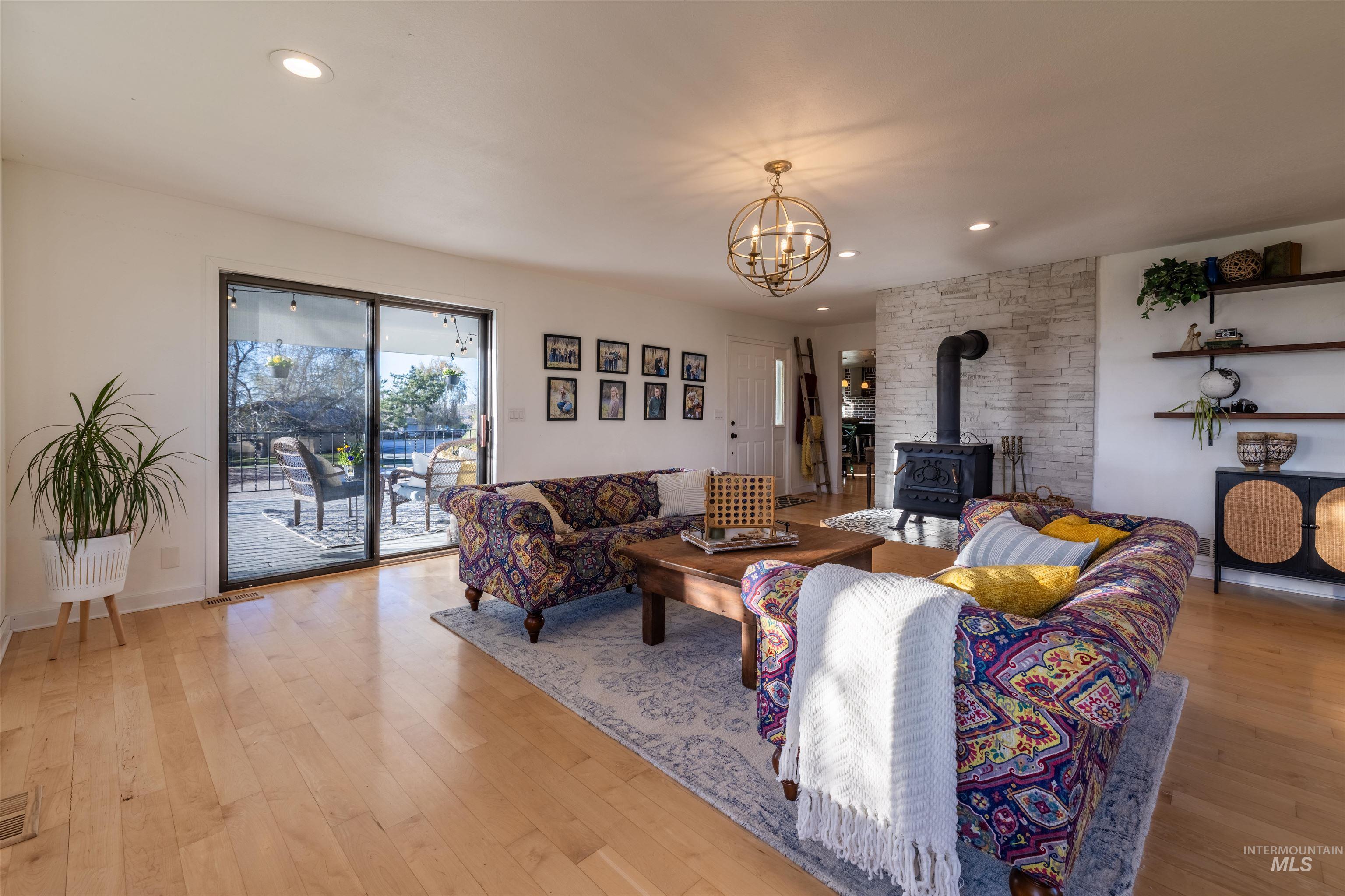 14526 Perfection Lane Caldwell, ID 83607 - Photo 3 of 24 Living area featuring light wood-finish flooring, recessed lighting, and a prominent wood-burning stove set against a stone-clad wall