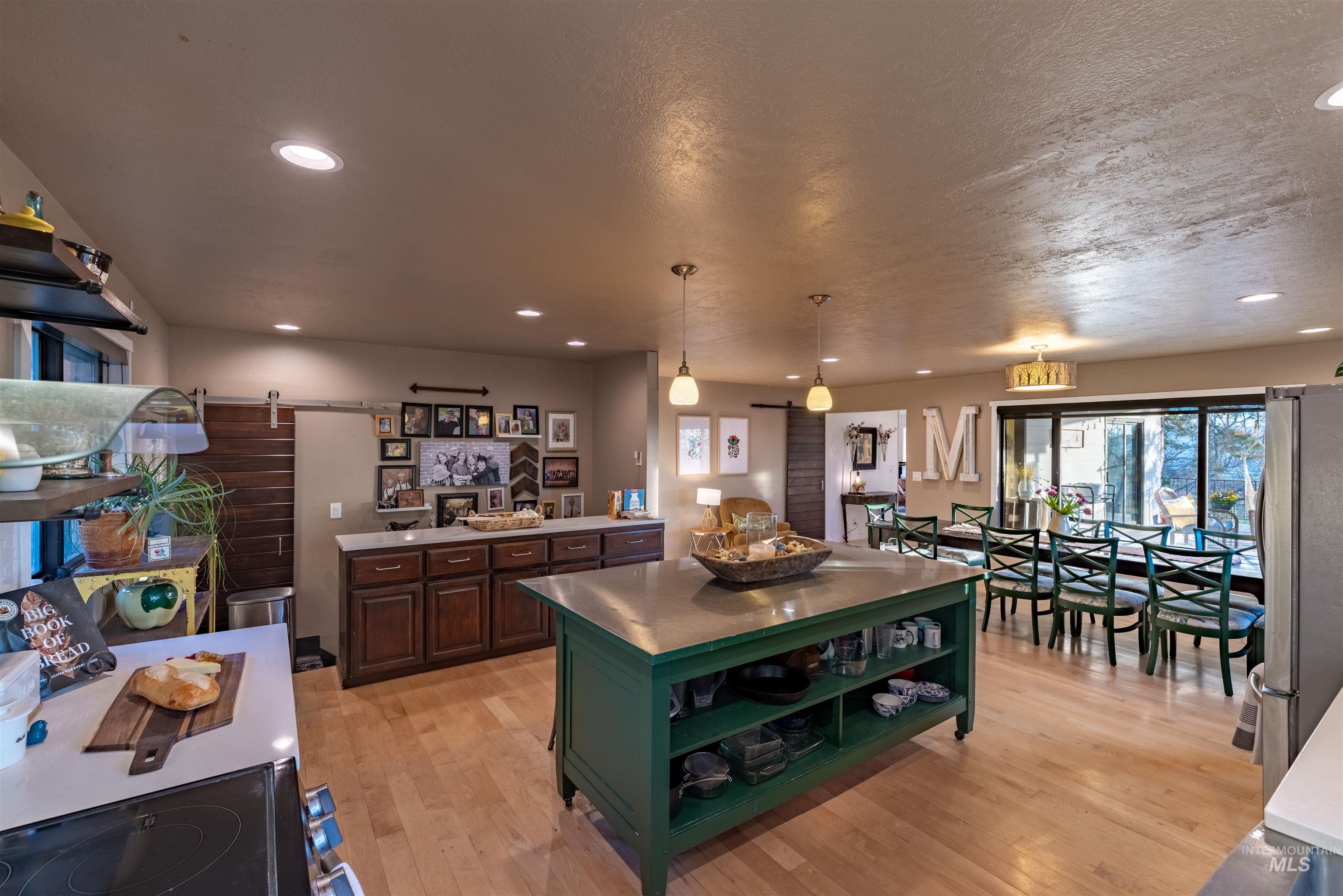 14526 Perfection Lane Caldwell, ID 83607 - Photo 5 of 24 Open-concept kitchen and dining area featuring light wood-finish flooring, recessed lighting, and a green kitchen island with open shelving