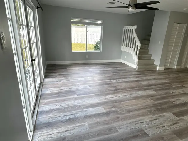 a view of an empty room with wooden floor and a kitchen