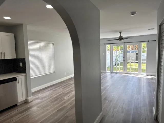 an empty room with wooden floor fan and windows