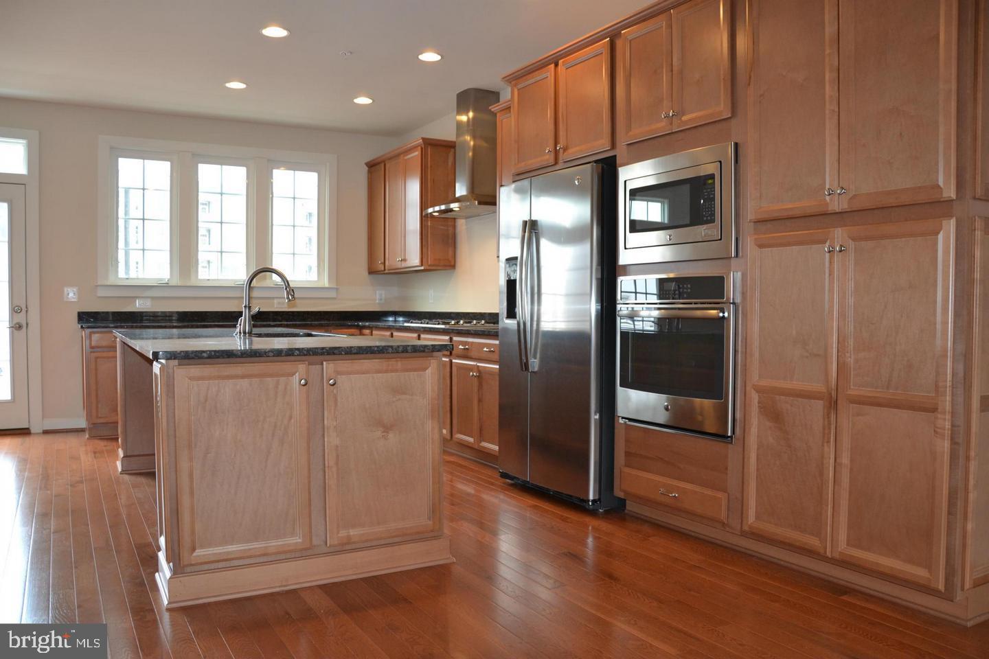 3174 Yeager Drive Herndon, VA 20171 - Photo 7 of 20 a kitchen with kitchen island granite countertop wooden cabinets and a refrigerator