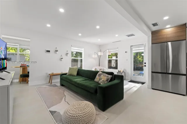 a living room with furniture and a refrigerator