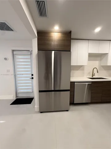 a kitchen with stainless steel appliances a refrigerator and a more cabinets