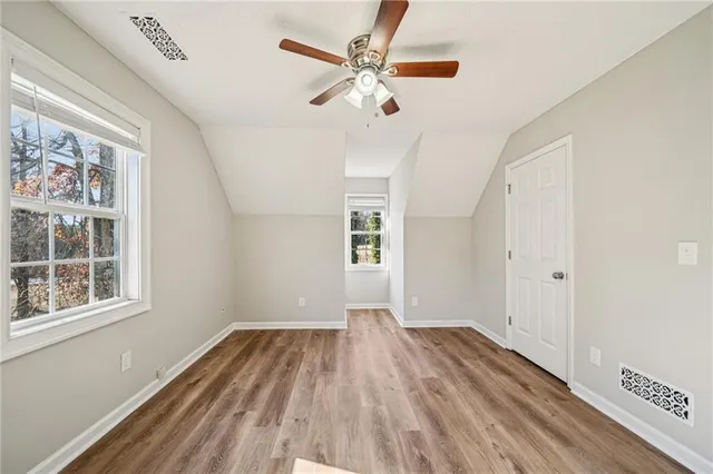 a view of empty room with wooden floor and fan